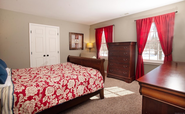 bedroom with a closet, visible vents, and carpet floors