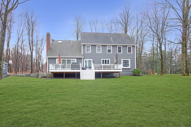 back of property featuring a wooden deck, a chimney, a yard, and a shingled roof