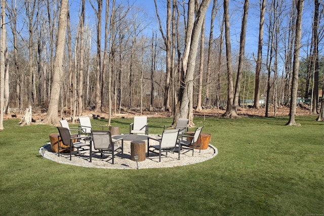 view of yard with a patio, a fire pit, and a view of trees