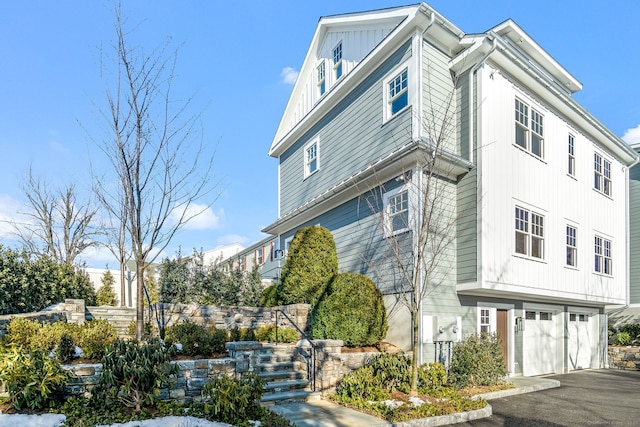 view of front of house featuring aphalt driveway, stairway, and an attached garage