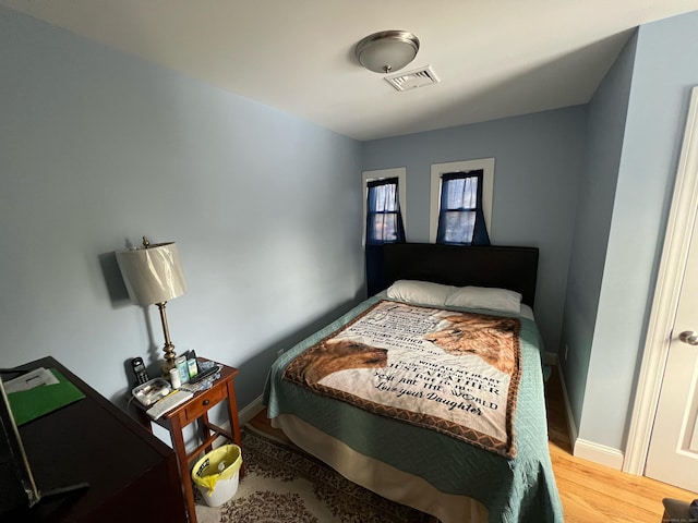 bedroom with visible vents, baseboards, and wood finished floors