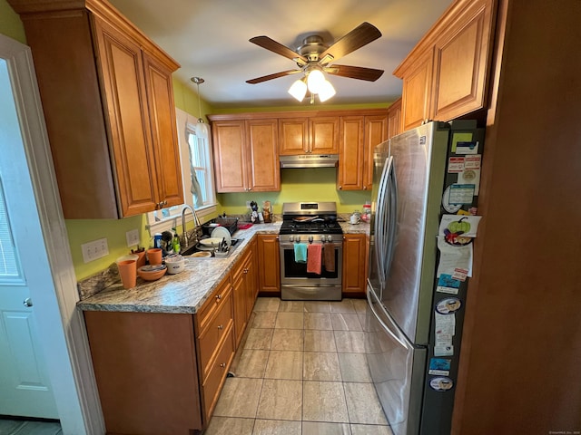 kitchen with stainless steel appliances, brown cabinetry, a sink, and under cabinet range hood