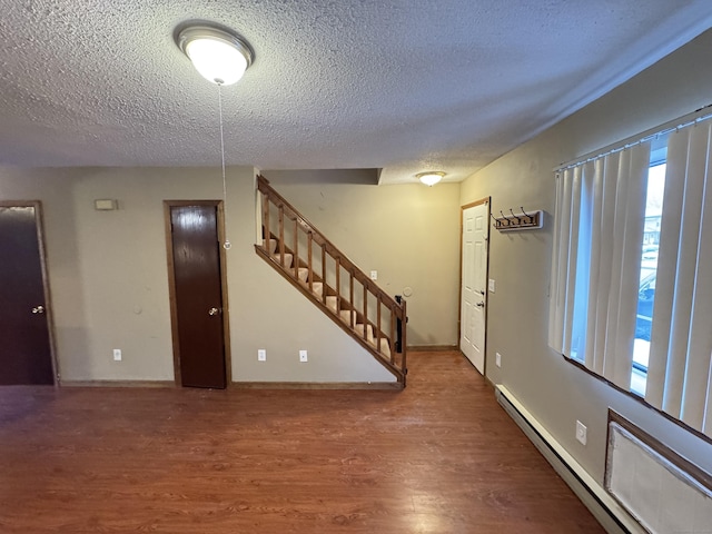 entrance foyer with baseboards, a baseboard radiator, stairway, wood finished floors, and a textured ceiling