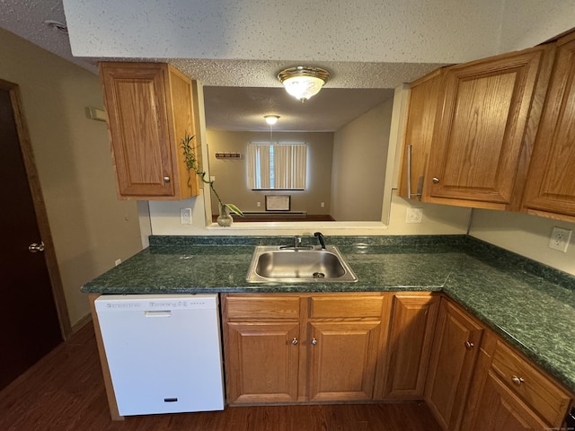 kitchen featuring a sink, a peninsula, brown cabinetry, and dishwasher