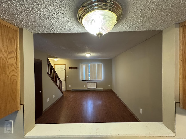 interior space featuring dark wood-style flooring, baseboard heating, a textured ceiling, baseboards, and stairs