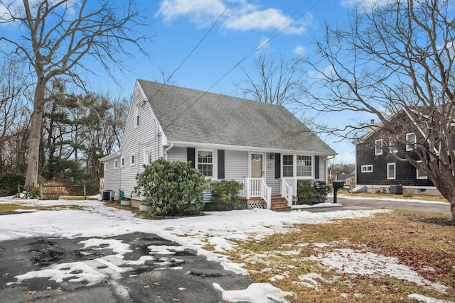 cape cod home featuring a shingled roof and cooling unit