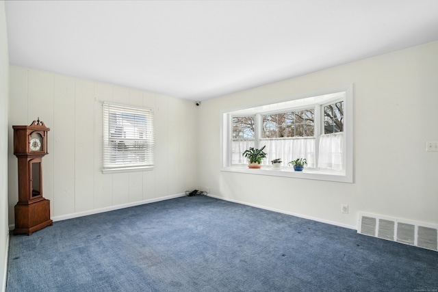 spare room with carpet floors, plenty of natural light, visible vents, and baseboards