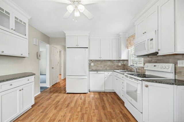 kitchen with white appliances, white cabinets, glass insert cabinets, a sink, and backsplash