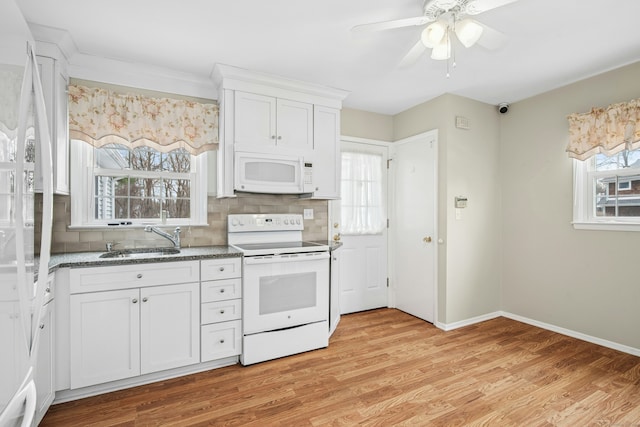 kitchen with white appliances, white cabinets, a sink, and light wood finished floors