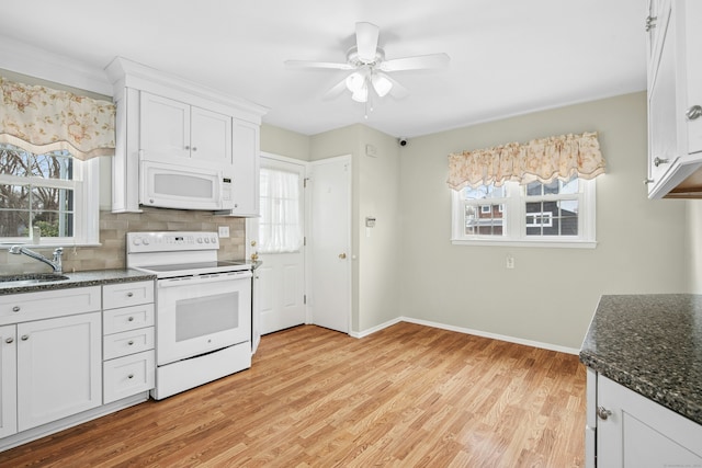 kitchen featuring backsplash, light wood-style floors, white cabinets, dark stone counters, and white appliances