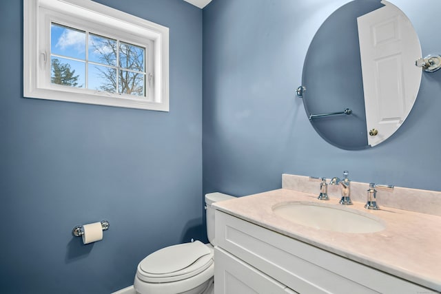 half bath featuring toilet, vanity, and baseboards