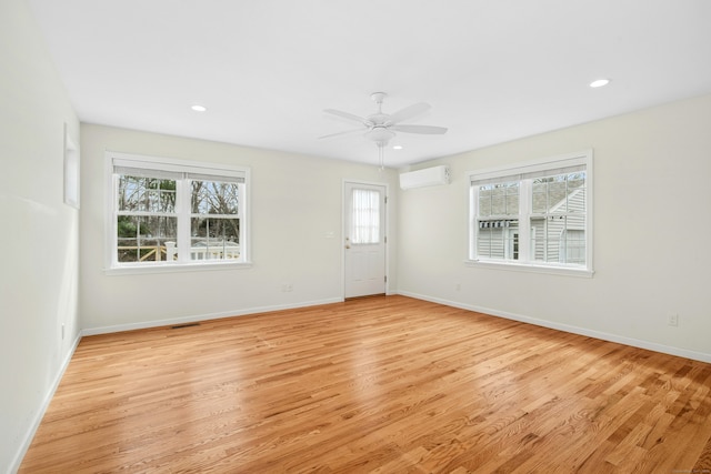 unfurnished room with light wood finished floors, baseboards, an AC wall unit, and recessed lighting