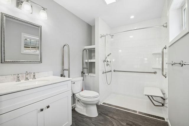 bathroom with toilet, tiled shower, and vanity