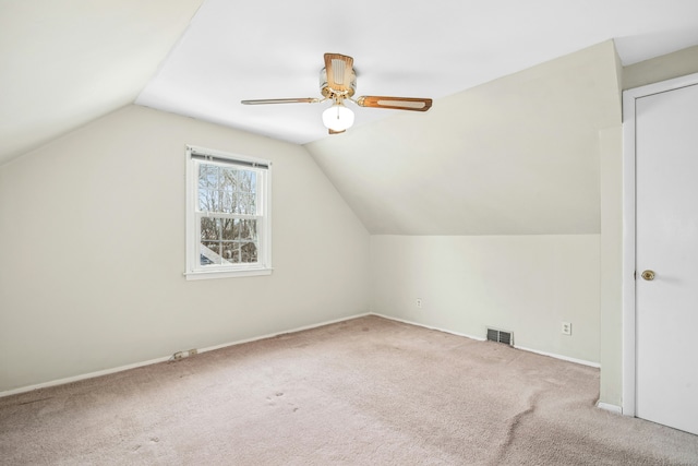 additional living space featuring light colored carpet, a ceiling fan, baseboards, vaulted ceiling, and visible vents