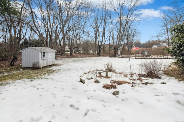 yard covered in snow featuring a storage shed and an outdoor structure