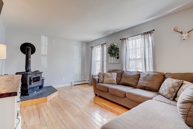 living room with a wood stove, baseboards, light wood-type flooring, and a baseboard radiator