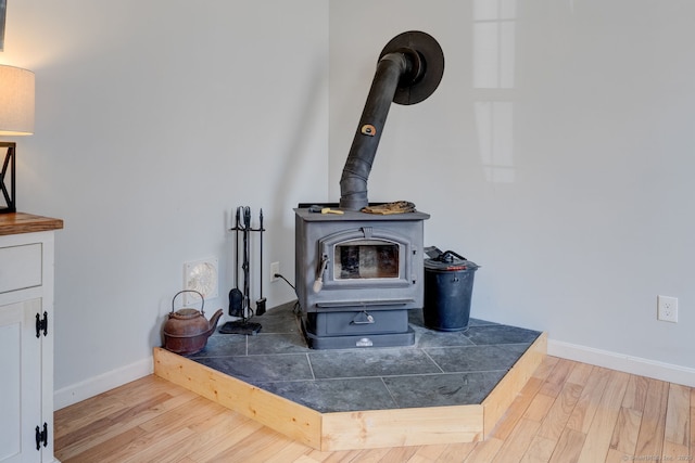 room details featuring baseboards, wood finished floors, and a wood stove