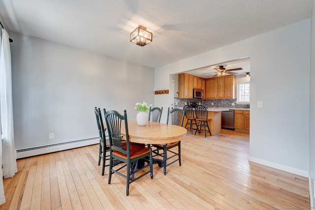 dining space with light wood-style floors, baseboards, baseboard heating, and a textured ceiling