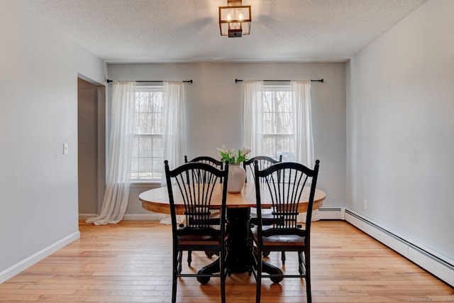 dining area featuring a wealth of natural light, light wood finished floors, and a baseboard radiator