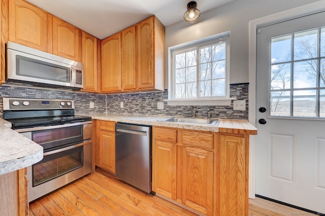 kitchen with light countertops, backsplash, appliances with stainless steel finishes, and a sink