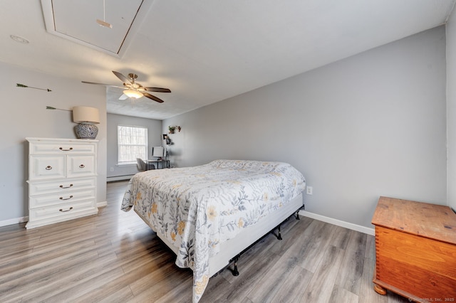 bedroom with light wood-style flooring, attic access, baseboards, and a ceiling fan