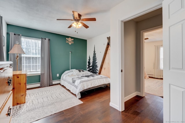 bedroom with wood finished floors, baseboards, baseboard heating, and ceiling fan