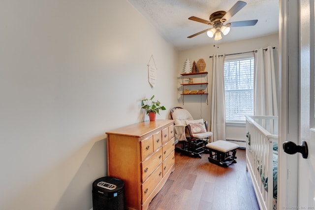 sitting room featuring a textured ceiling, baseboard heating, ceiling fan, and hardwood / wood-style flooring