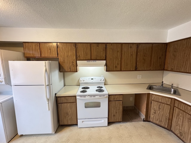 kitchen featuring light countertops, a sink, a textured ceiling, white appliances, and under cabinet range hood