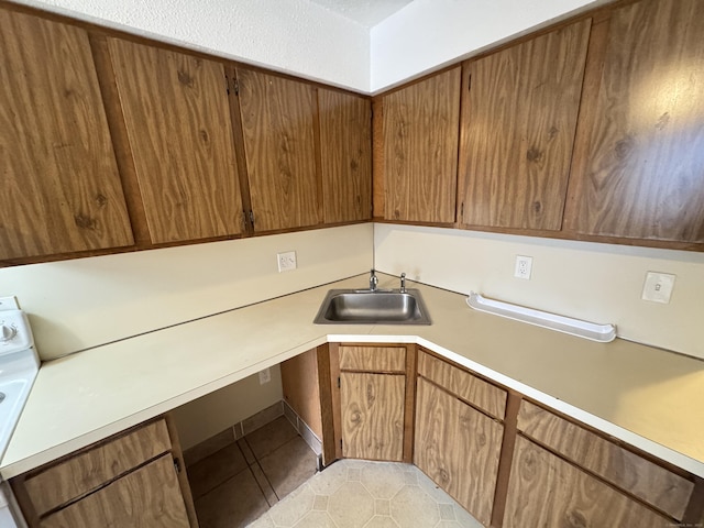 kitchen with brown cabinetry, light countertops, and a sink