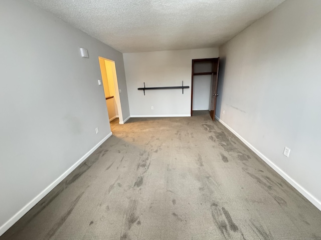 carpeted empty room with baseboards and a textured ceiling