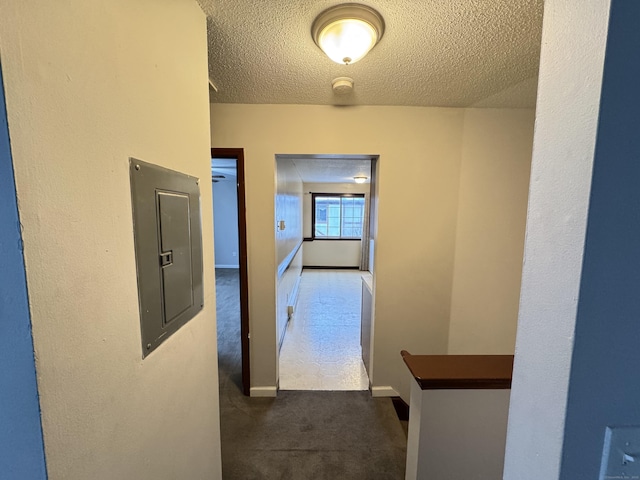 corridor featuring baseboards, electric panel, dark carpet, and a textured ceiling