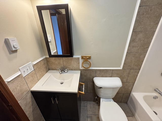 full bath featuring toilet, tile walls, vanity, and a tub