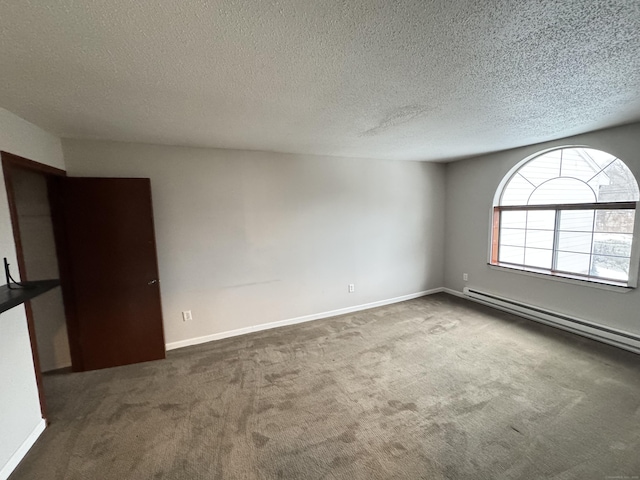 spare room with a baseboard heating unit, a textured ceiling, dark carpet, and baseboards