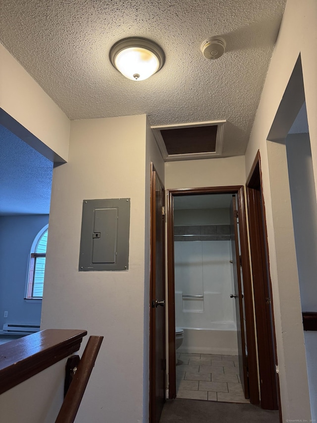 corridor with a textured ceiling, dark tile patterned flooring, a baseboard radiator, and electric panel