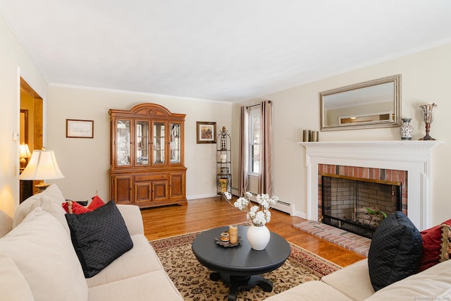 living area with ornamental molding, a fireplace, light wood-style flooring, and baseboards