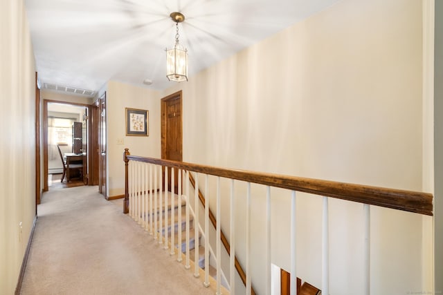 corridor with light carpet, visible vents, an upstairs landing, and baseboards