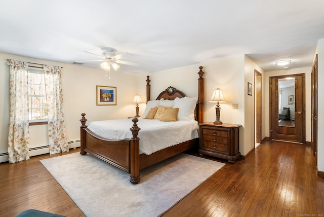 bedroom with a baseboard heating unit, dark wood finished floors, baseboards, and ceiling fan