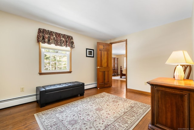 sitting room featuring baseboards, baseboard heating, and wood finished floors