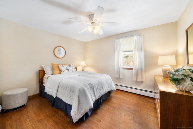 bedroom featuring a baseboard radiator, ceiling fan, baseboards, and wood finished floors