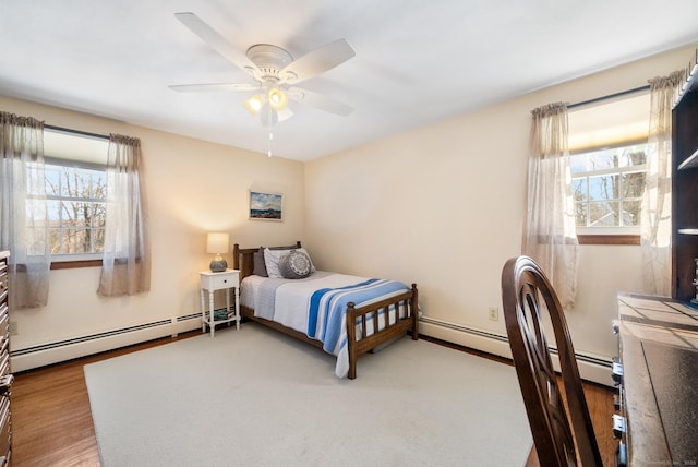 bedroom with ceiling fan, a baseboard radiator, and wood finished floors