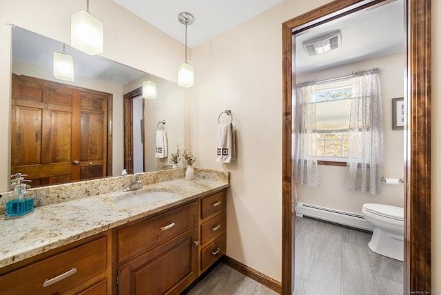 bathroom featuring toilet, baseboards, a baseboard heating unit, and vanity