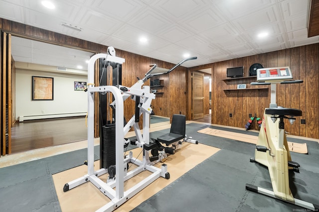 workout room featuring a baseboard radiator, visible vents, and wood walls