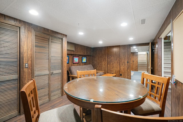 dining space featuring wood walls, visible vents, and light wood-style floors