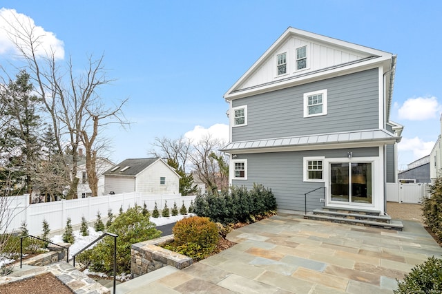 rear view of house with entry steps, a standing seam roof, fence, and board and batten siding