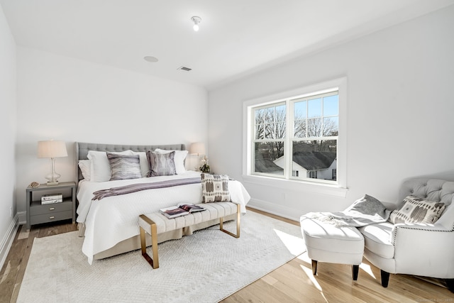 bedroom featuring wood finished floors, visible vents, and baseboards