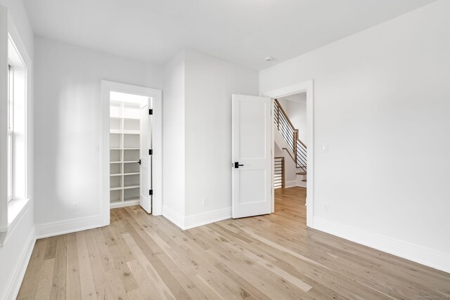 25 Henry St Unit B, Greenwich, CT 06830 - unfurnished bedroom featuring a walk in closet, baseboards, a closet, and light wood-style flooring