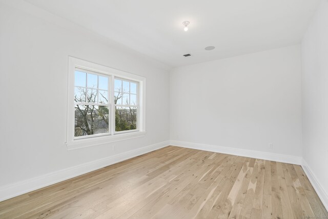 spare room featuring light wood-style floors, visible vents, and baseboards