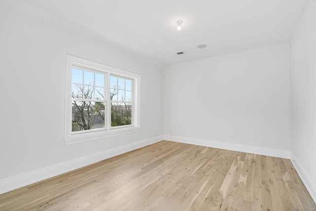 spare room featuring light wood-style floors, visible vents, and baseboards