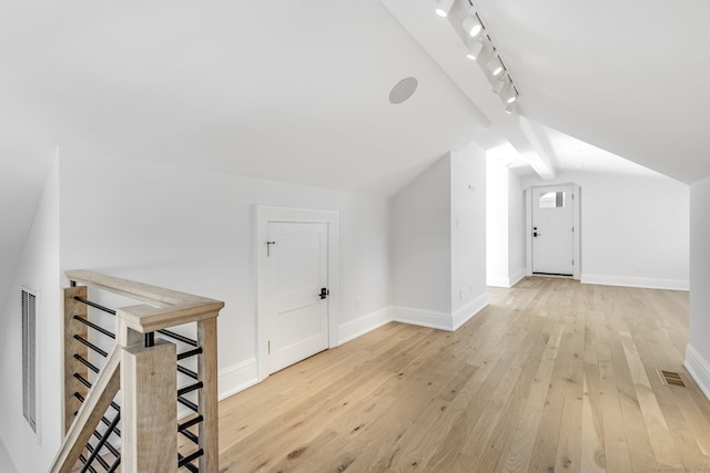 additional living space with baseboards, visible vents, light wood-style floors, and vaulted ceiling