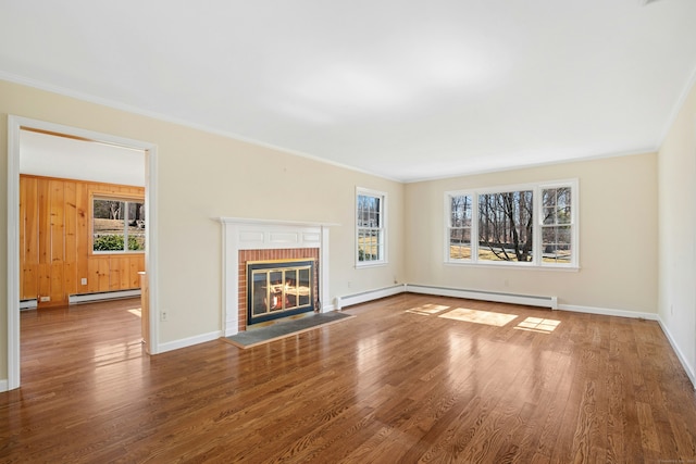 unfurnished living room featuring ornamental molding, wood finished floors, baseboard heating, a fireplace, and a baseboard heating unit